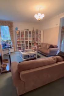 A child sits in a living room with two sofas, a coffee table, and large bookshelves.