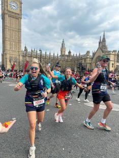 Three people running a marathon in London, with Big Ben in the background.