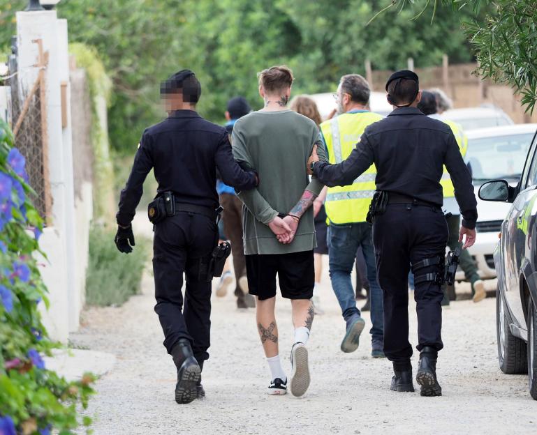 A man in handcuffs escorted by two police officers.