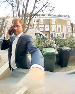 Prince Harry on a phone call outside a building in Fulham.