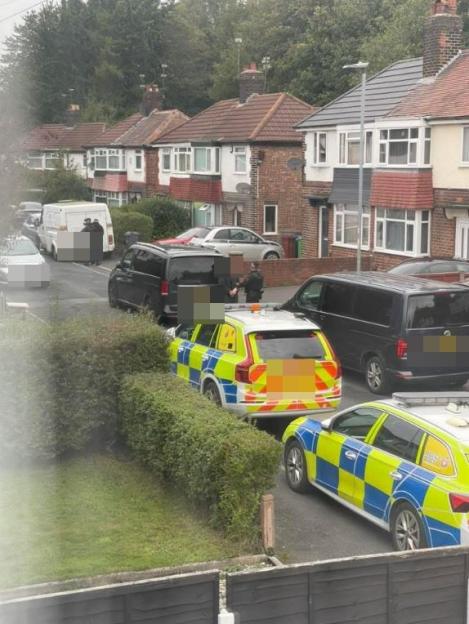 Two police cars and two police officers blocking a street in a residential area.