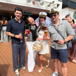 Four people on a cruise ship, two men and two women, one of whom is dressed as a bride.