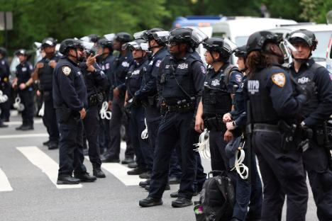 NYPD officers standing in formation near a protest.