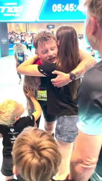 Man embracing a woman and child after a triathlon.