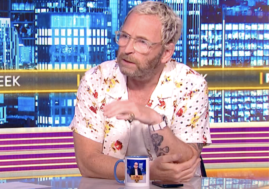 Man in floral shirt on a talk show.