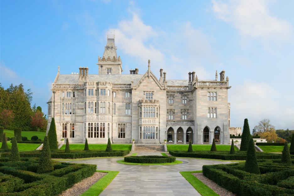 Gothic Revival-style manor house with a manicured formal garden in the foreground.