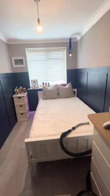American-style bedroom makeover with navy blue walls and white bed.