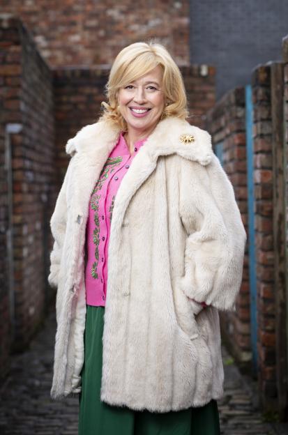 Katy Cavanagh as Julie Carp in a white faux fur coat.