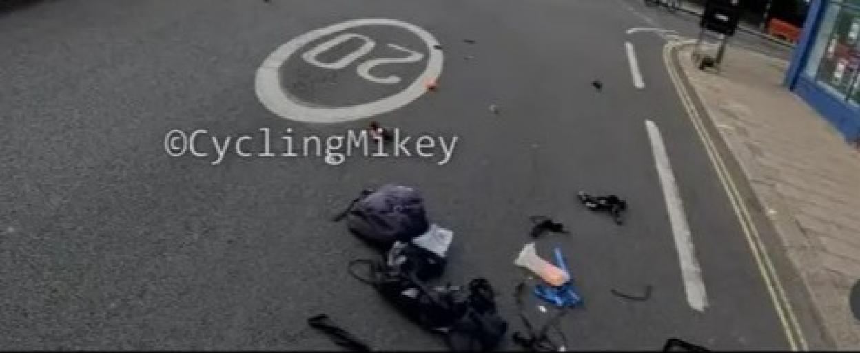 Cyclist's belongings scattered on the road after a collision near roadworks.
