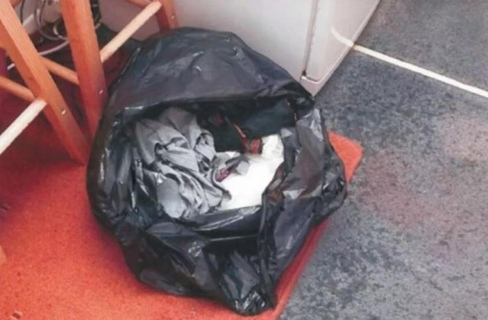A black bin bag containing duct tape and clothing.