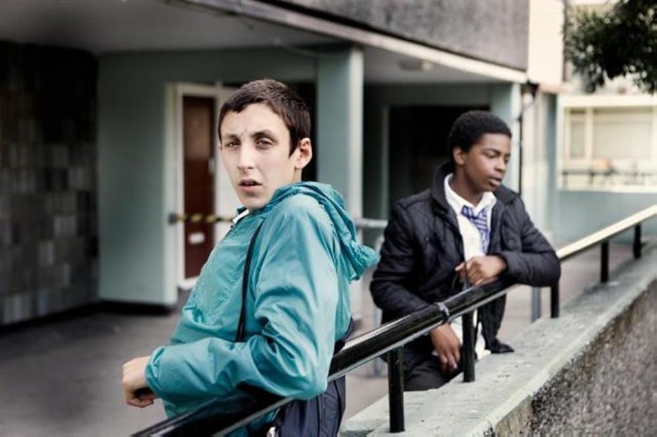 Two teenage boys leaning on a railing.