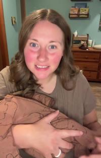 Woman holding baby in brown bear pajamas.