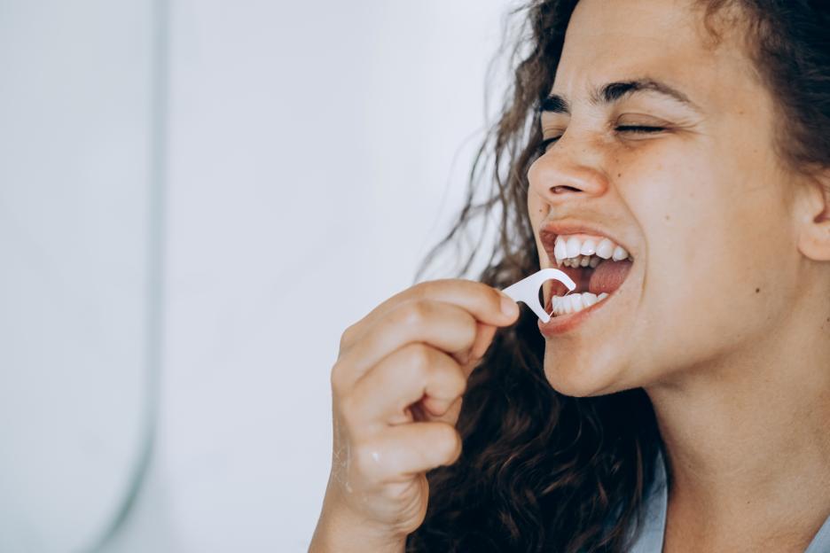 Young brunette woman flossing her teeth