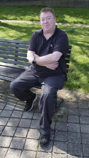 Man sitting on a park bench with his arms crossed.
