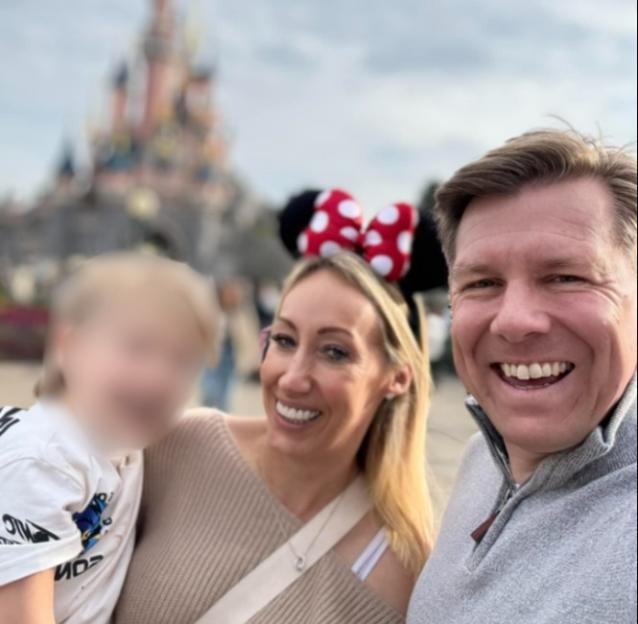 Katie and Danny Bloomfield with a child in front of a castle.