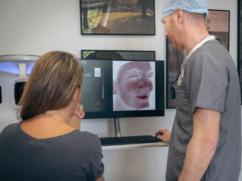 Skin damage test results shown on a computer screen to a patient and doctor.