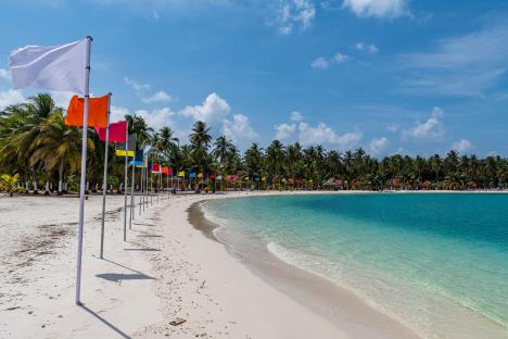 White sand beach with colorful flags on Bangaram Island.