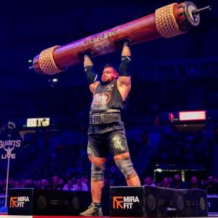 Strongman lifting a heavy log overhead.