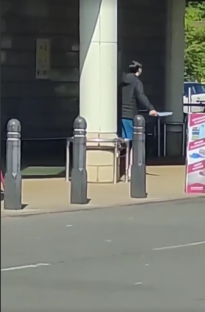 Person carrying a long object near a building.