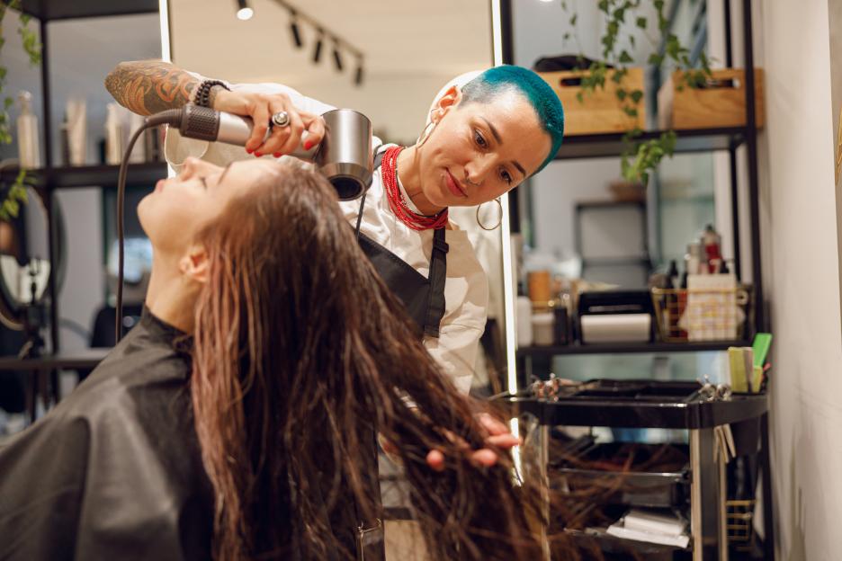 Hairdresser blow-drying a client's hair.