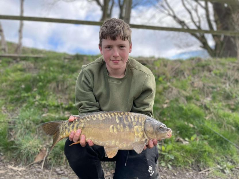 Teenager holding a large carp.