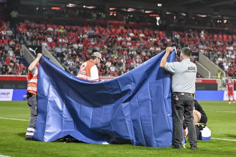 Medical personnel shielding an injured soccer player on the field with a privacy screen.