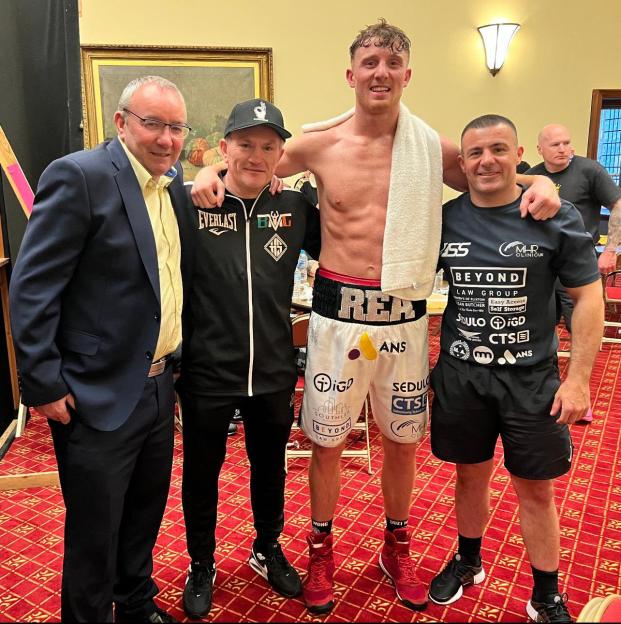 A boxer and three men posing for a photo.