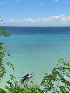 Boat in turquoise water viewed from above.