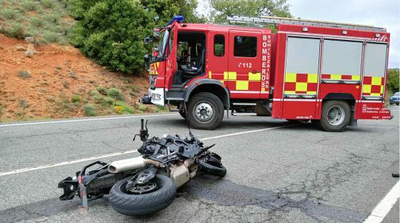 A wrecked motorcycle and a firetruck at the scene of a fatal accident.