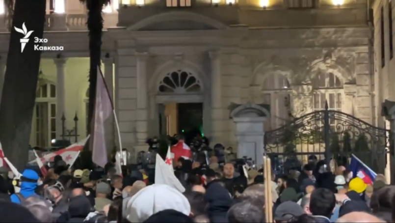 A crowd of protesters gathered in front of a building at night.