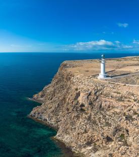 Aerial view of a lighthouse on a cliff overlooking the sea.
