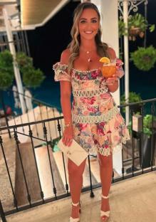 Woman in floral dress holding a cocktail.