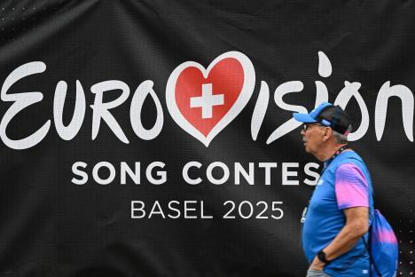 A man walks past a Eurovision Song Contest Basel 2025 banner.