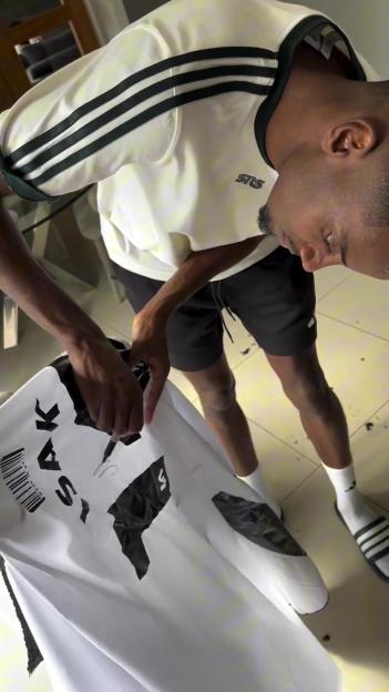 Alexander Isak signing a white cape with the words "MADE IN KAY" on it.