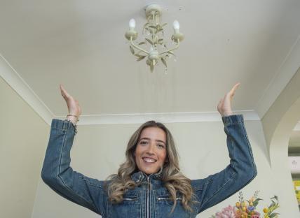 Woman in denim jacket admiring a new chandelier.