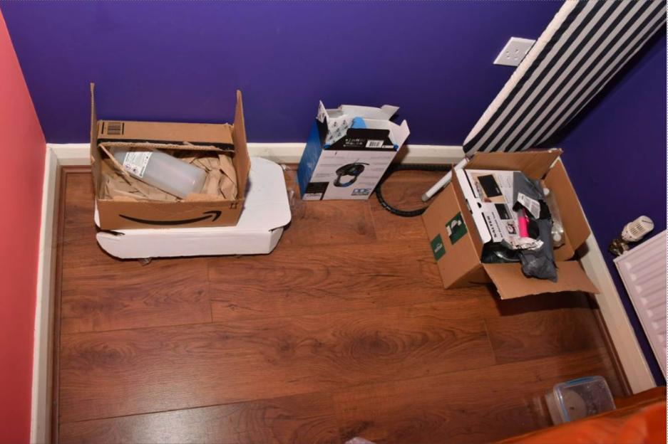 Items found on a bedroom floor, including boxes, packaging materials, and what appears to be a plastic bottle and headphones.
