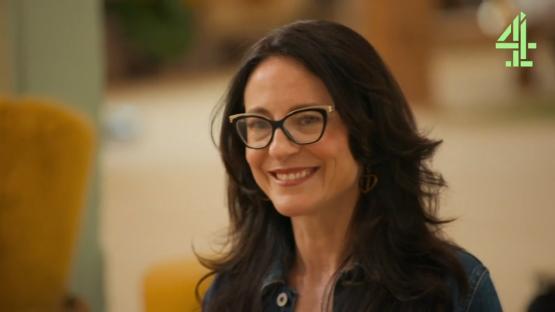 A woman smiling and wearing glasses.