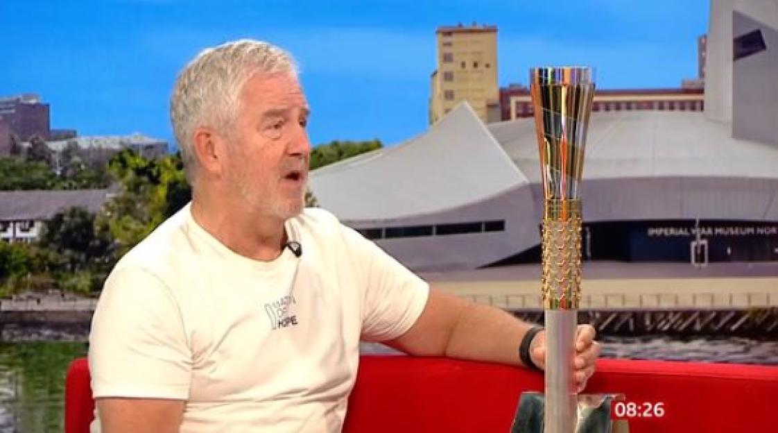 A Sky News presenter holding a baton, appearing emotional.