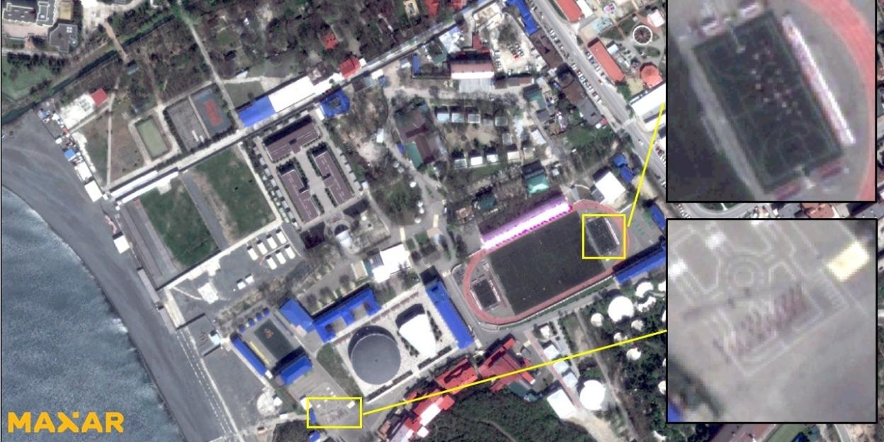 Satellite imagery showing dark specks consistent with individual personnel in organized formations at a location in Russia.