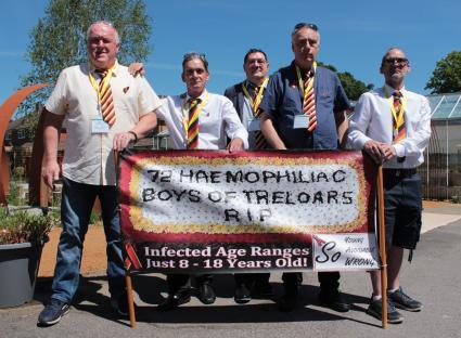 Five men holding a banner that reads