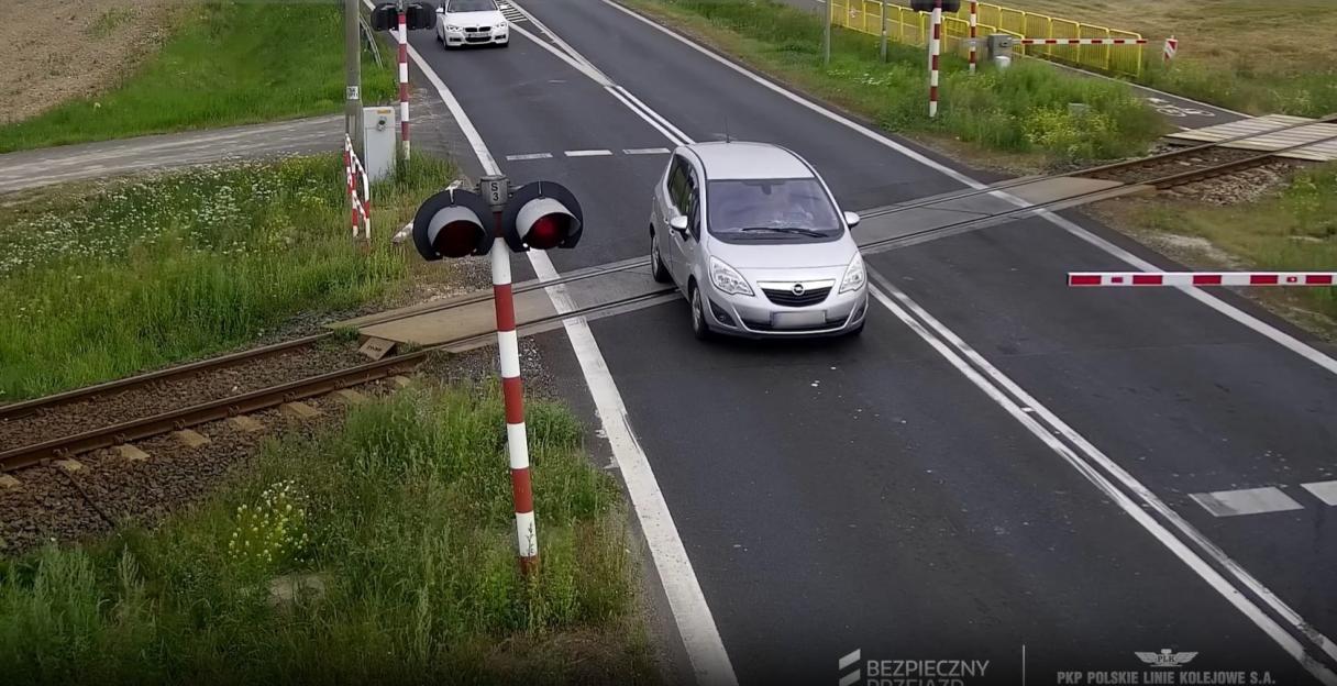 Car crashes through railway barrier and is hit by train.