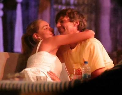 Louis Tomlinson and Zara McDermott embracing at a beachside restaurant.