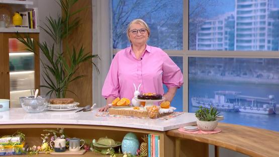 Woman in pink shirt presenting a chocolate orange cake.
