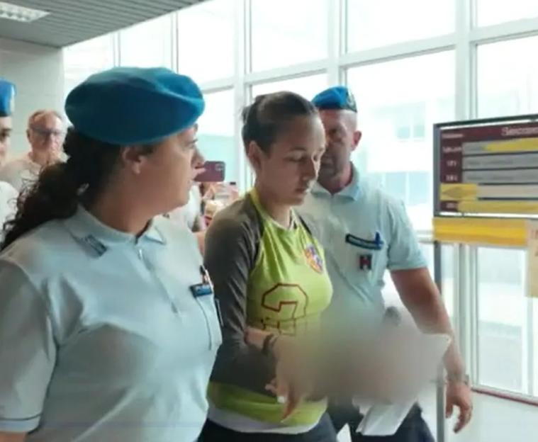 A woman escorted by police.