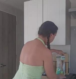 Woman in a light green jumpsuit in a static caravan kitchen.
