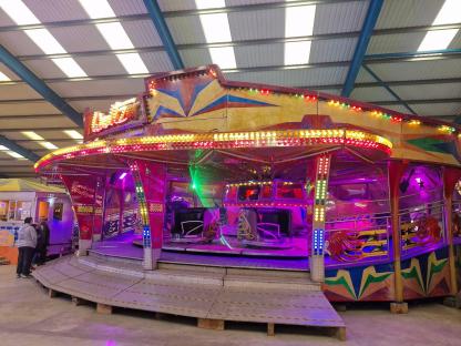 A brightly lit waltzer ride at an indoor fun park.