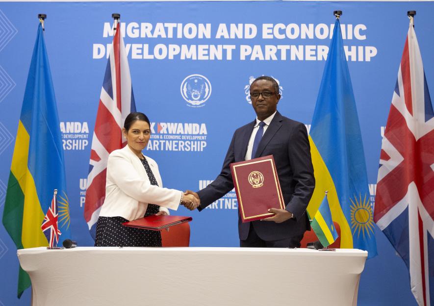 UK and Rwandan officials shaking hands at a migration partnership signing ceremony.