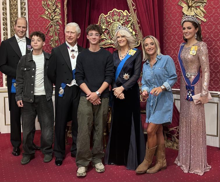 People posing with wax figures of the British Royal Family at Madame Tussauds.