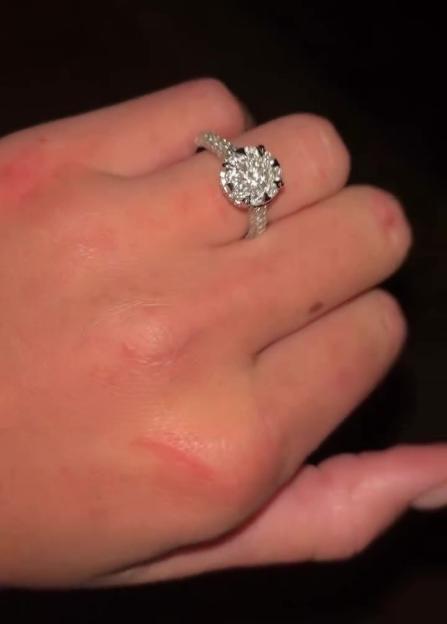 A hand wearing a dazzling engagement ring.