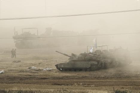 Israeli tanks parked in a dusty staging area near the Gaza border.